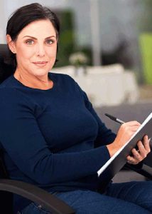 therapist sitting in chair with notepad and pen